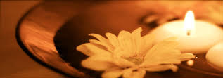 Warm light from candles and flower floating in bowl of water